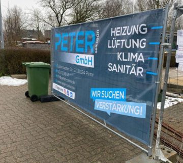 Ein Baustellenzaun mit einem Banner der Firma Peter GmbH