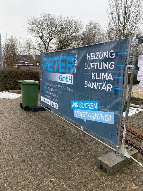 Ein Baustellenzaun mit einem Banner der Firma Peter GmbH
