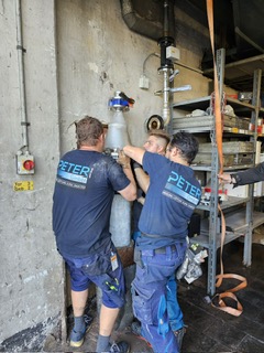 Drei Monteure arbeiten im Keller an einem Rohr